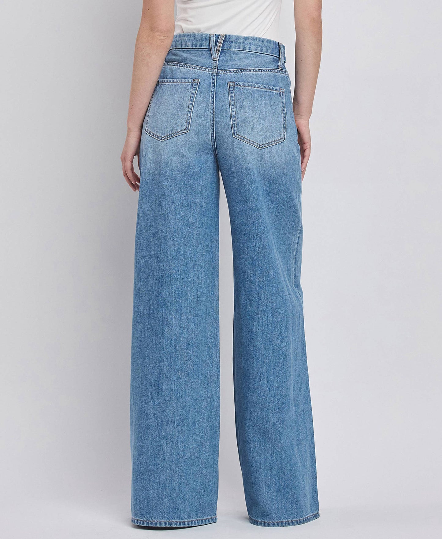 Blue jeans worn by a person on a plain background