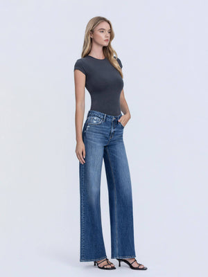 Woman wearing a dark gray t-shirt and blue jeans on a white background