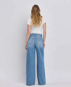 Person wearing blue jeans and a white shirt on a plain background