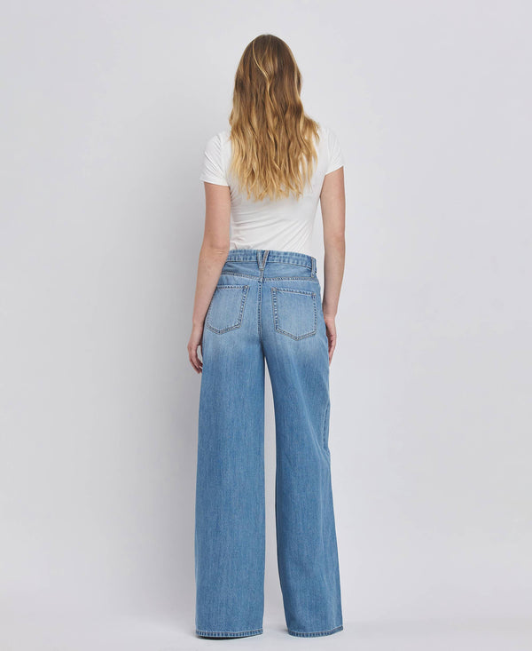 Person wearing blue jeans and a white shirt on a plain background