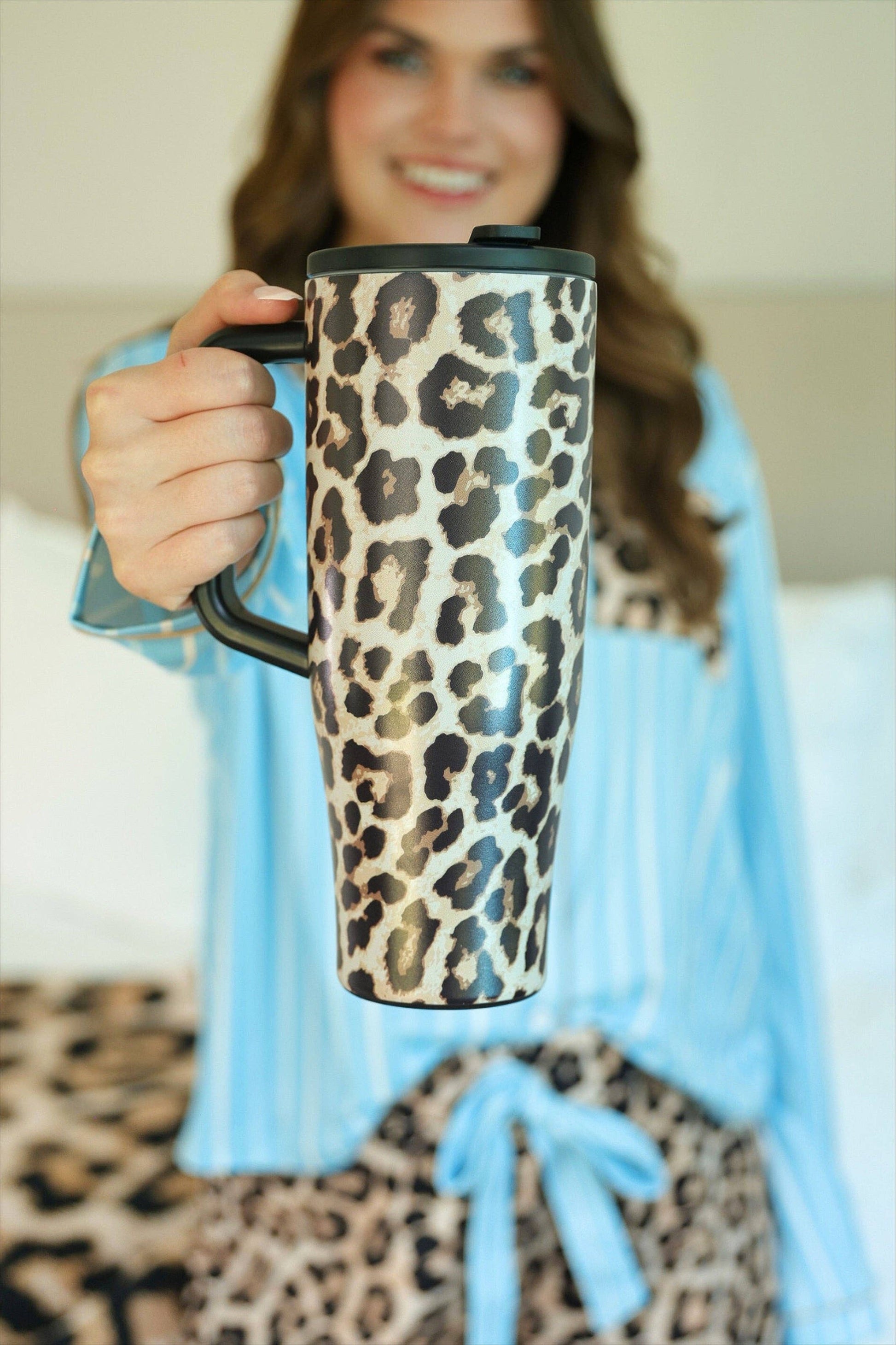 Person holding a leopard print mug with a blurred background