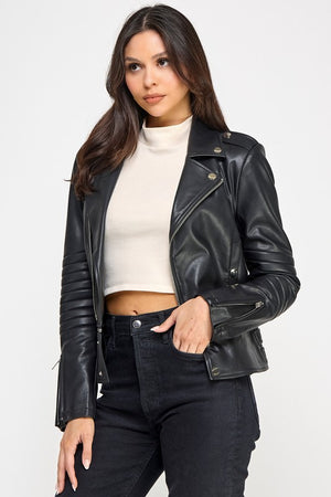 Woman wearing a black leather jacket over a white top and black pants on a white background