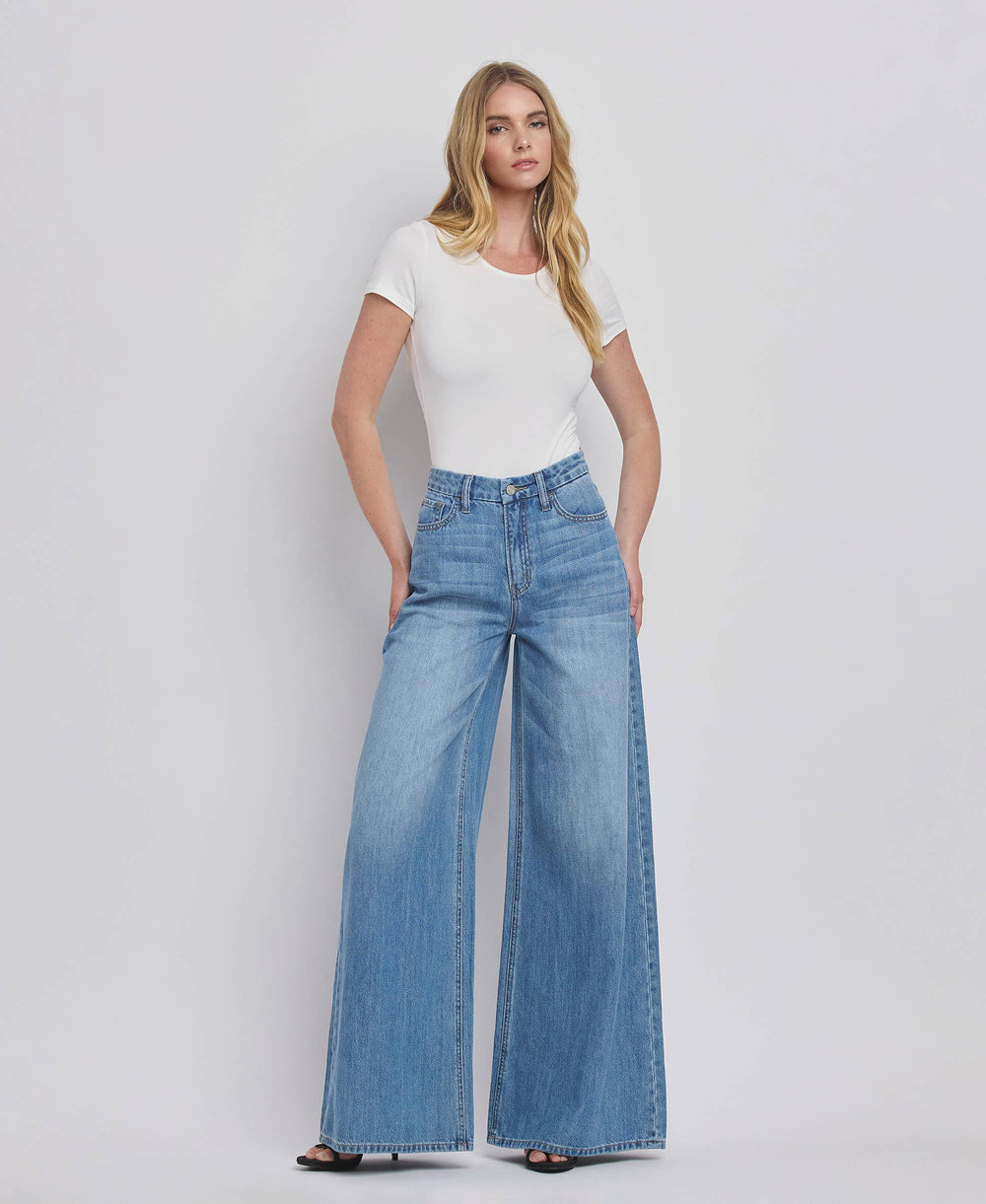 Woman wearing a white t-shirt and blue jeans on a plain background