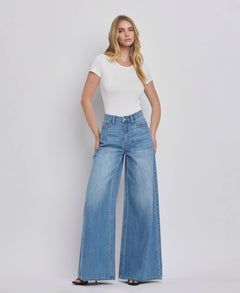 Woman wearing a white t-shirt and blue jeans on a plain background