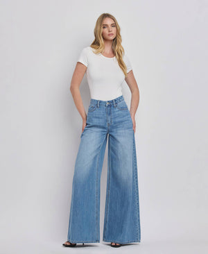 Woman wearing a white t-shirt and blue jeans on a plain background