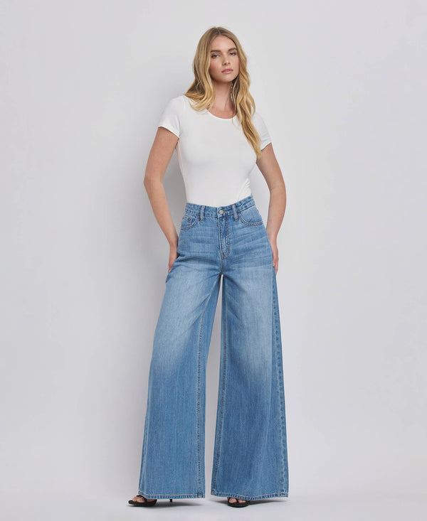 Woman wearing a white t-shirt and blue jeans on a plain background