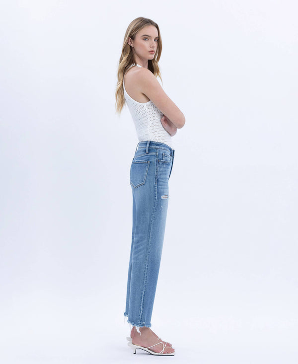 Woman wearing a white tank top and light blue jeans on a white background