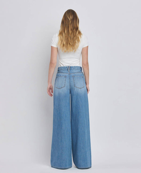 Person wearing blue jeans and a white shirt on a plain background