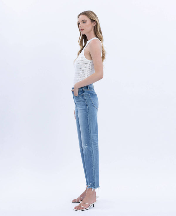 Woman wearing a white sleeveless top and blue jeans on a white background
