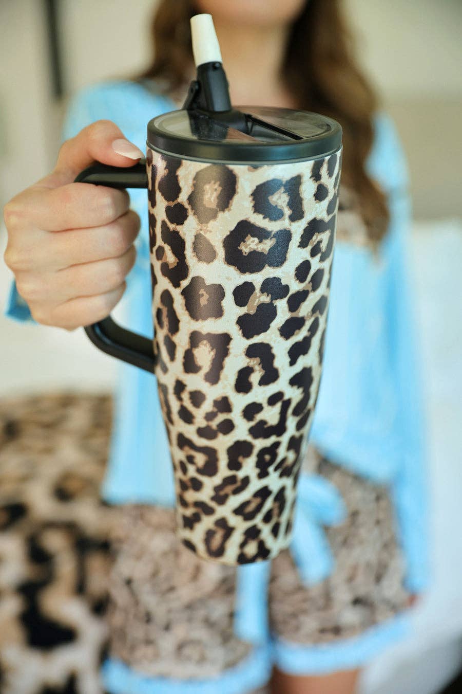 Leopard print tumbler held by a person wearing a blue sweater.