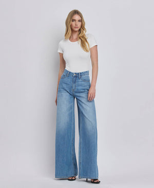 Woman wearing a white t-shirt and blue jeans on a plain background