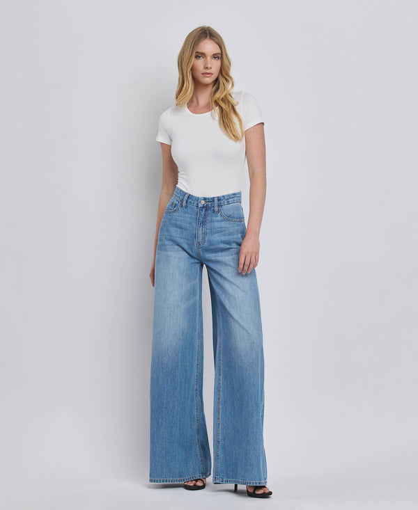 Woman wearing a white t-shirt and blue jeans on a plain background