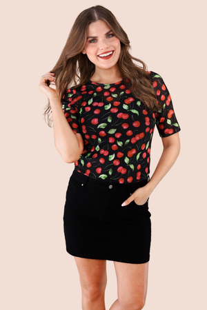 Woman wearing a black t-shirt with red cherry pattern on a beige background