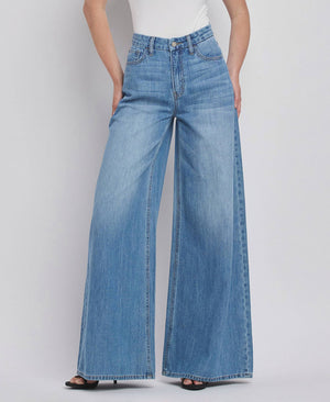 Person wearing blue wide-leg jeans on a plain background