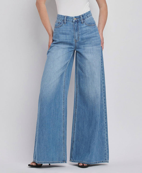 Person wearing blue wide-leg jeans on a plain background