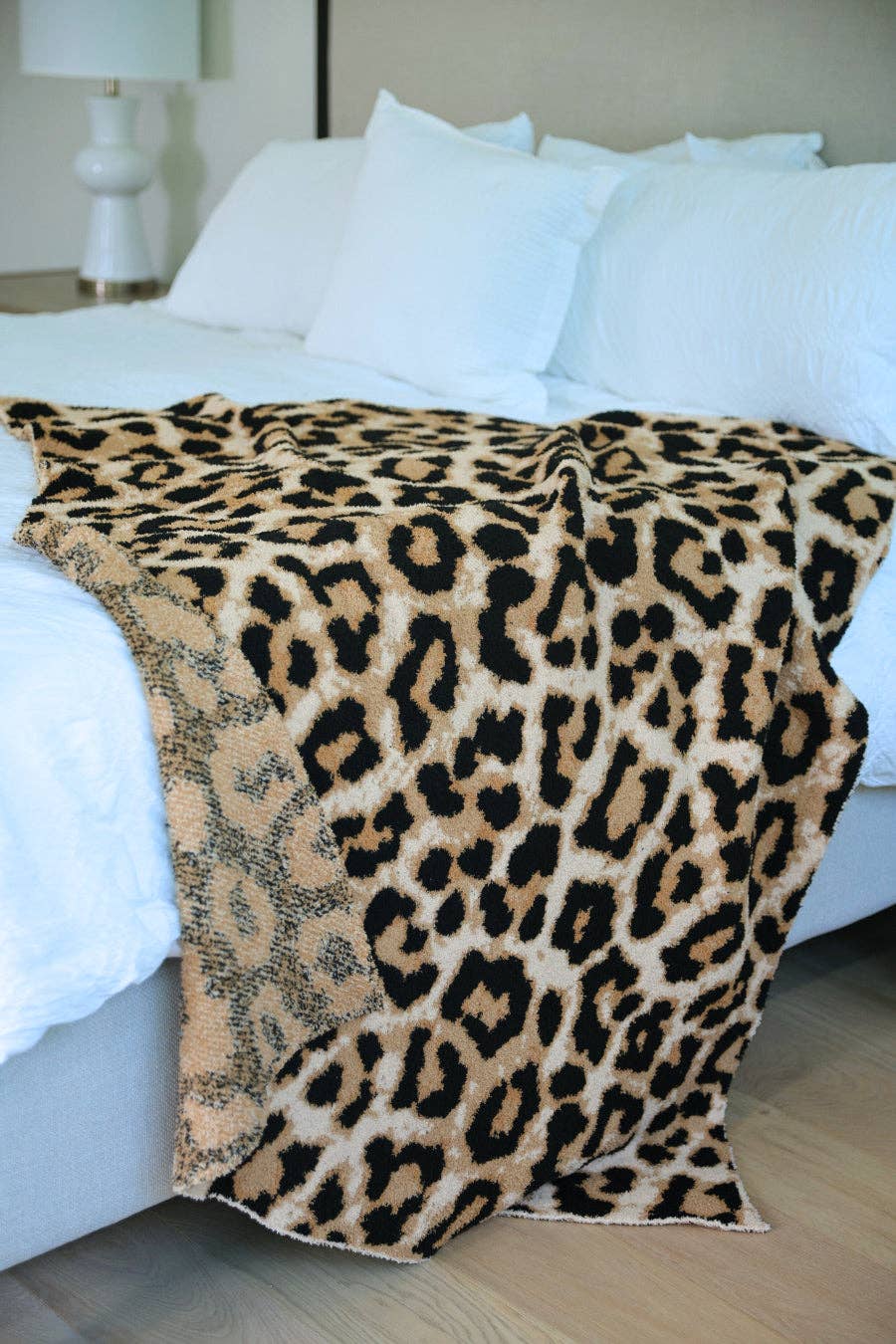 Leopard print blanket draped over a bed with white pillows.