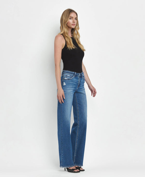 Woman wearing blue jeans and a black top on a white background