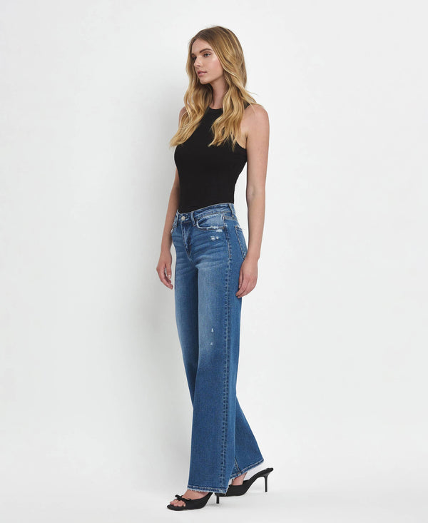 Woman wearing blue jeans and a black top on a white background