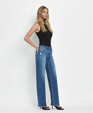 Woman wearing blue jeans and a black top against a white background
