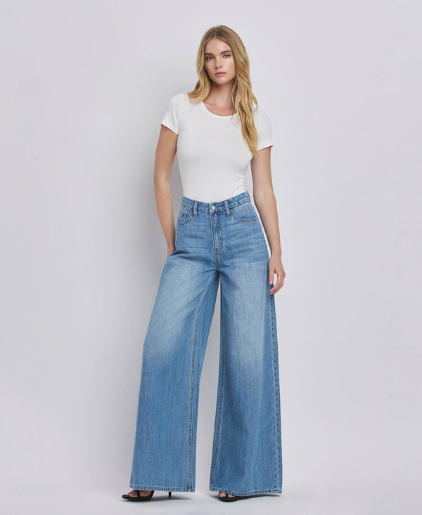 Woman wearing a white top and blue jeans on a plain background
