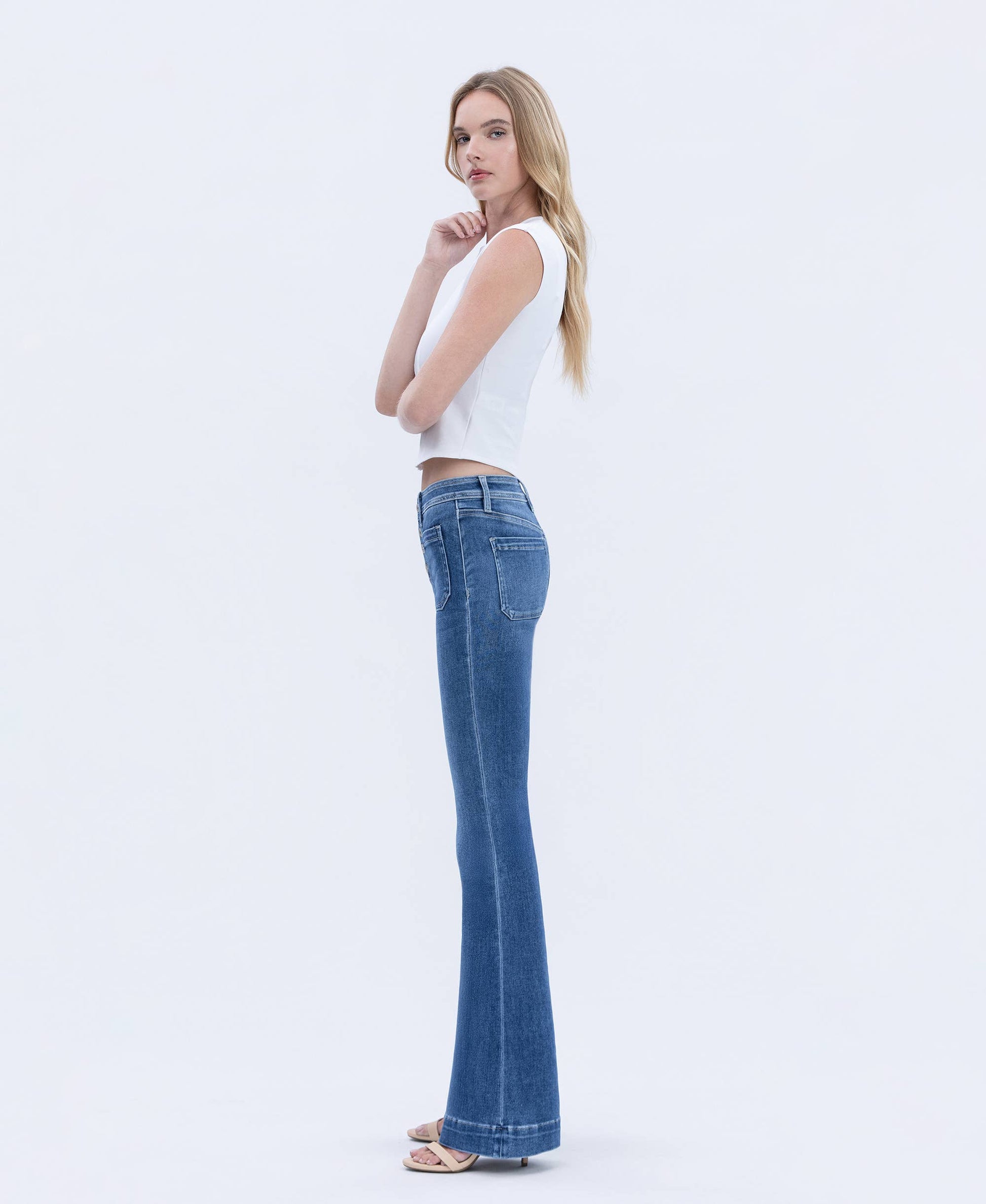 Woman wearing a white sleeveless top and blue jeans on a white background