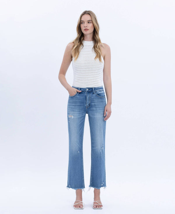 Woman wearing a white sleeveless top and blue jeans on a white background