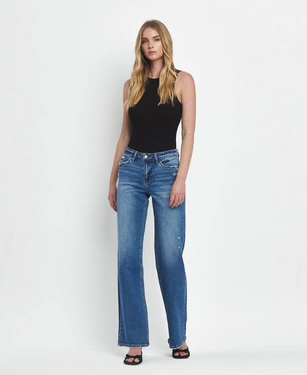 Woman wearing blue jeans and a black top on a white background