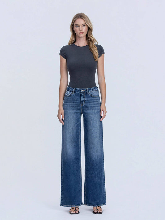 Woman wearing a dark gray t-shirt and blue jeans on a white background