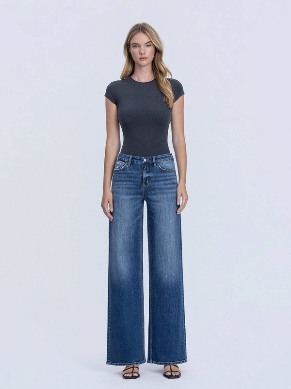 Woman wearing a dark gray t-shirt and blue jeans on a white background