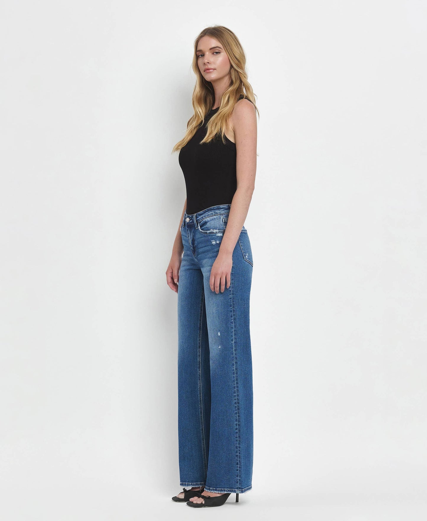 Woman wearing blue jeans and a black top on a white background