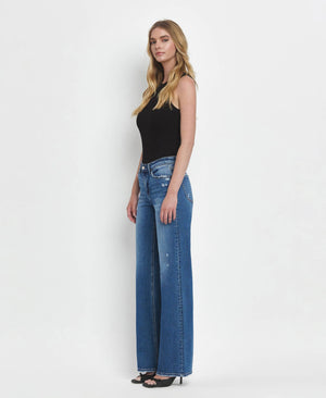 Woman wearing blue jeans and a black top on a white background