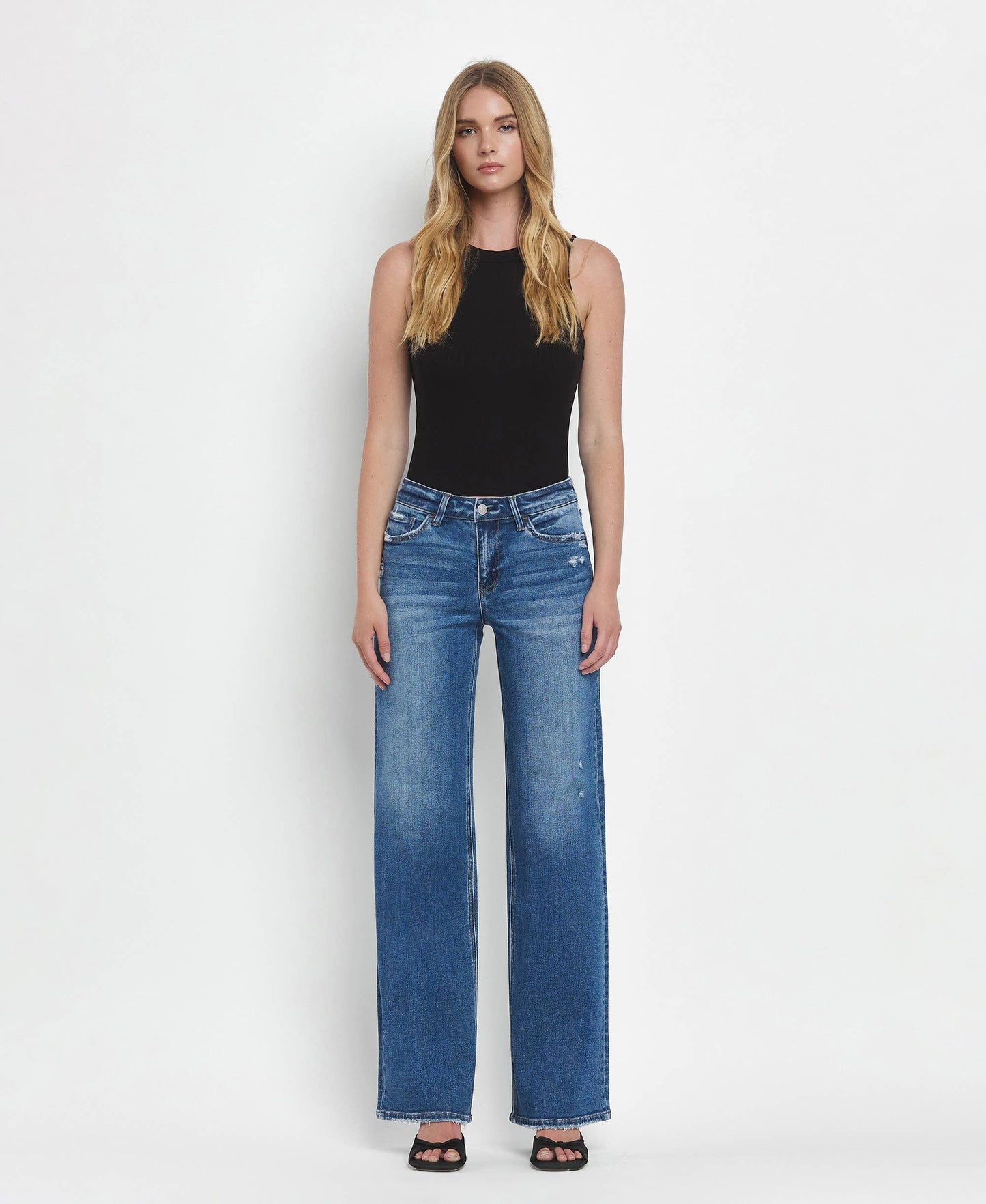 Woman wearing blue jeans and a black top on a white background