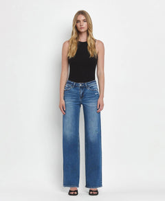 Woman wearing blue jeans and a black top on a white background