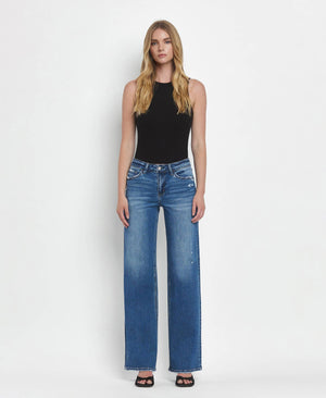 Woman wearing blue jeans and a black top on a white background