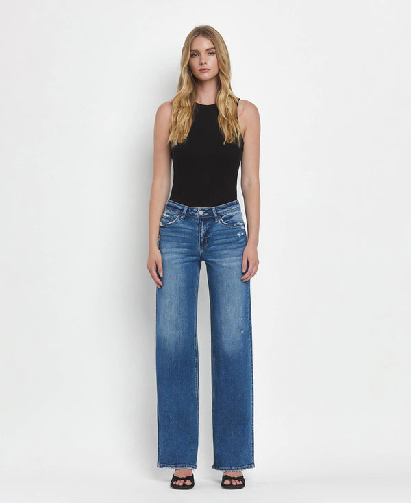 Woman wearing blue jeans and a black top on a white background