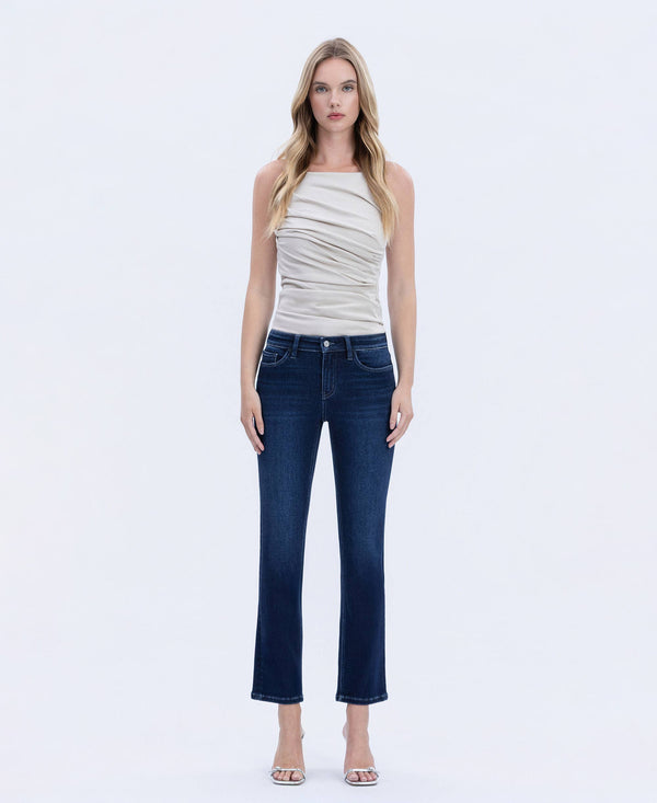 Woman wearing dark wash straight-leg jeans with a flattering mid-rise fit, styled with a neutral ruched sleeveless top, shown in front view.