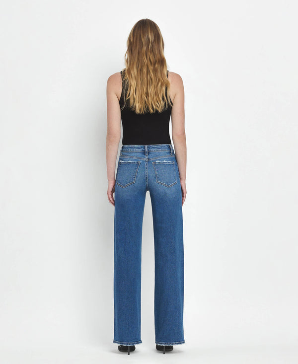 Person wearing blue jeans and a black top on a white background