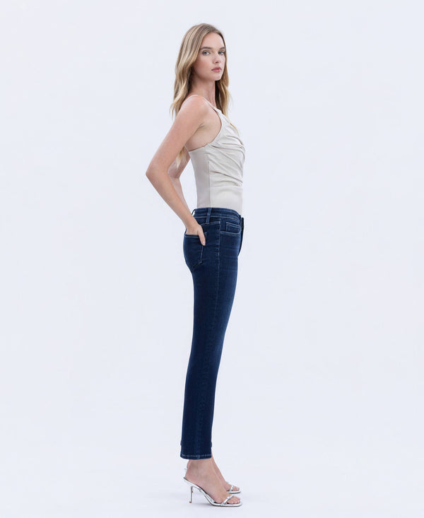 Side view of woman wearing dark wash straight-leg jeans with a mid-rise fit, styled with a neutral sleeveless top and heels.