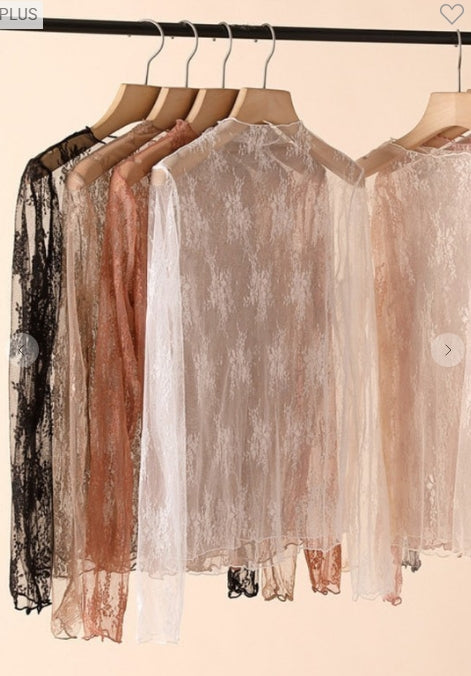 Sheer dresses in black, brown, and white hanging on a rack against a beige background.