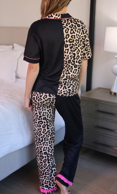 Person wearing a leopard print and black outfit in a bedroom setting.