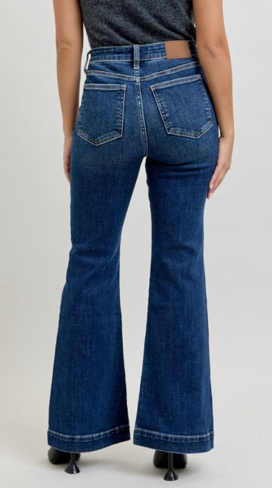 Person wearing blue flared jeans on a plain background