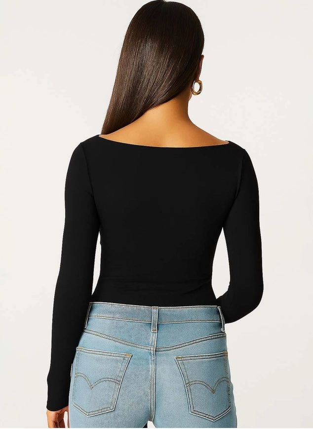 Person wearing a black long-sleeve top and blue jeans on a white background