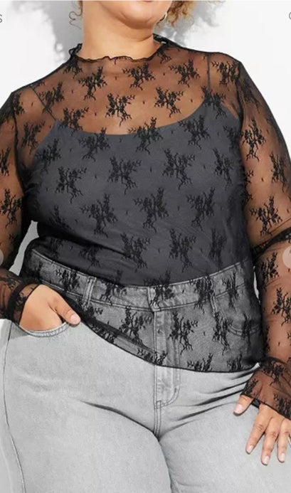 Person wearing a black lace top with sheer sleeves and gray pants.
