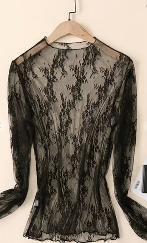 Black lace top on a wooden hanger against a white background