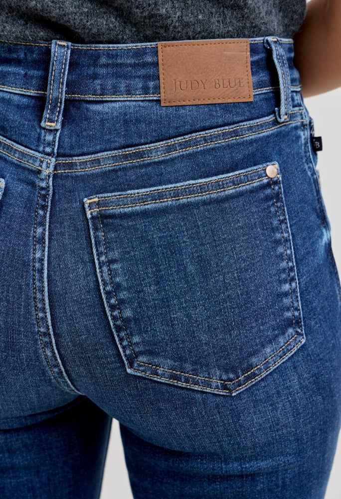 Close-up of blue jeans with a brand label on the back pocket against a neutral background