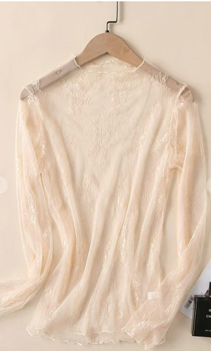 Beige lace top on a hanger against a plain background