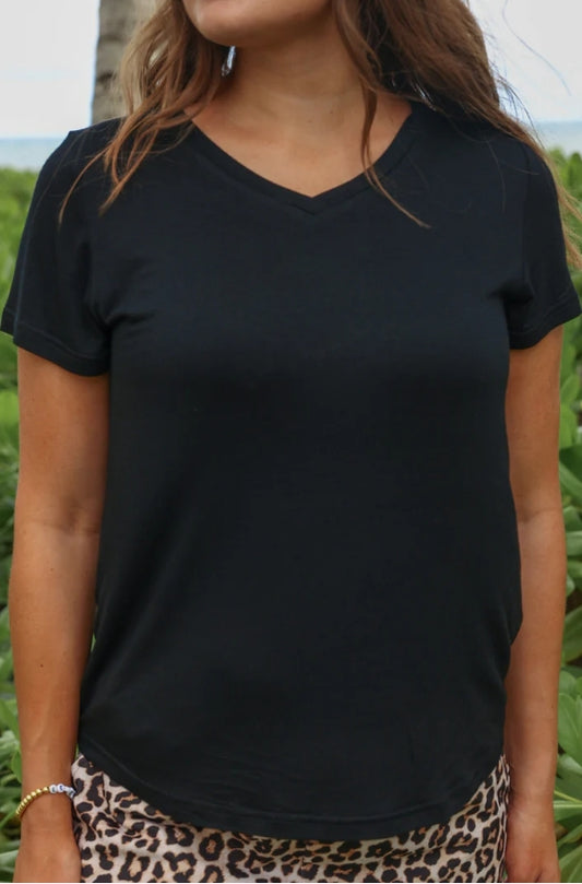 Person wearing a black V-neck t-shirt with a blurred natural background
