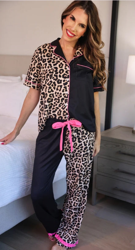 Woman wearing leopard print pajamas with a pink belt in a bedroom setting.