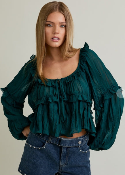 Woman wearing a green blouse, denim shorts, and brown knee-high boots on a white background