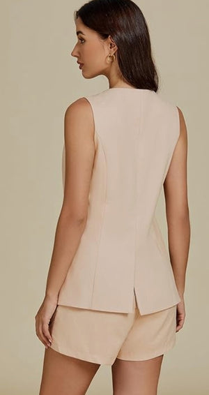 Woman wearing a beige sleeveless top and shorts against a beige background